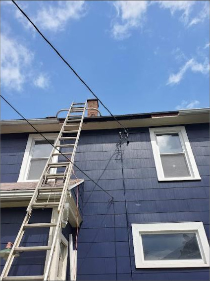 Ladder set to the roofline for gutter and fascia work on a two-story house