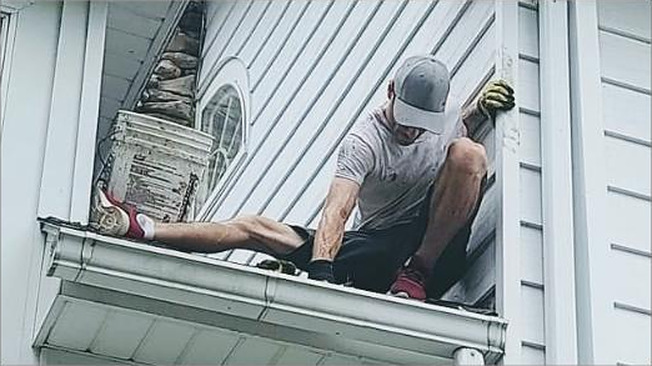 Beddia Contracting crew member working on a gutter line from the roof edge